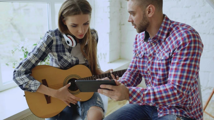 Man and woman learning guitar from phone